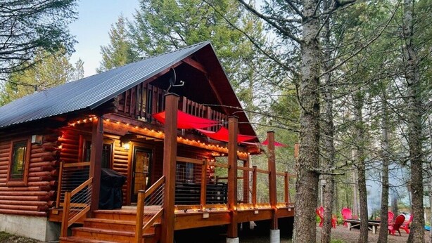 Eine Blockhütte mit Veranda, Treppen und Lichterkette.