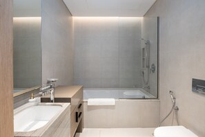 Un baño moderno con dos lavamanos, una bañera y una ducha.