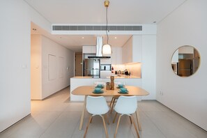 Una cocina moderna con una isla central, armarios blancos y un espejo redondo en la pared.