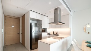 Eine moderne Küche mit einem eingebauten Kühlschrank, einem Edelstahlherd und einer zentralen Kochinsel mit Spüle.