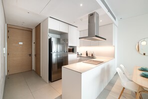 Une cuisine moderne dotée d’un réfrigérateur encastré, d’une cuisinière en acier inoxydable et d’un îlot central avec un évier.