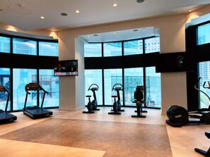A modern gym with treadmills, stationary bikes, and elliptical machines.