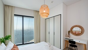 Ein Hotelzimmer mit Bett, Schreibtisch, Stuhl, einem großen Fenster mit Aussicht und einer Hängelampe.