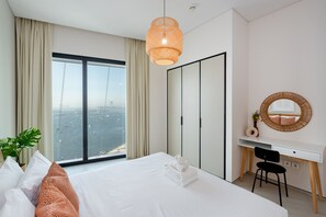 Une chambre d’hôtel comprenant un lit, un bureau, une chaise, une grande fenêtre avec vue et un luminaire suspendu.
