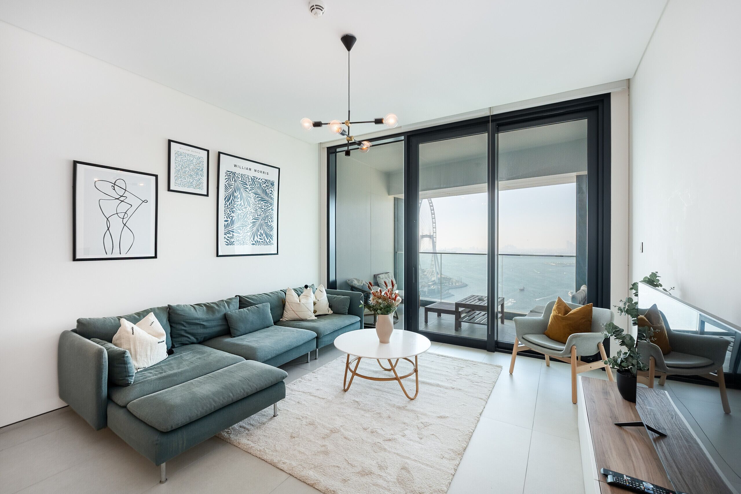 Un salon moderne avec un canapé, une table basse et une vue sur un pont, visible à travers de grandes fenêtres.