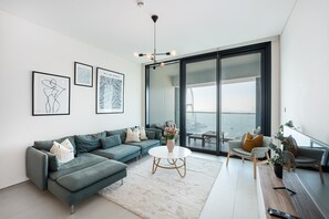 Un salon moderne avec un canapé, une table basse et une vue sur un pont, visible à travers de grandes fenêtres.