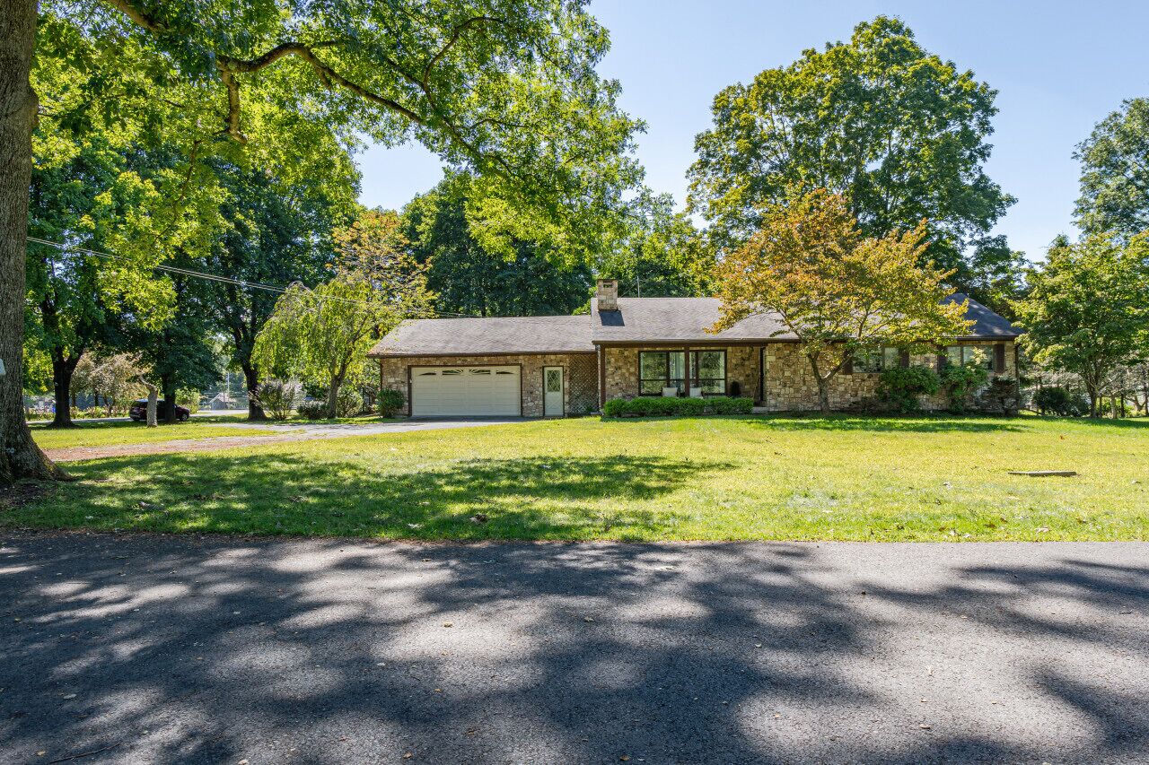 A two-story house with a garage, surrounded by a well-maintained lawn and trees.
