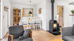 Una sala de estar acogedora con chimenea, paredes blancas y un comedor con mesa y sillas.