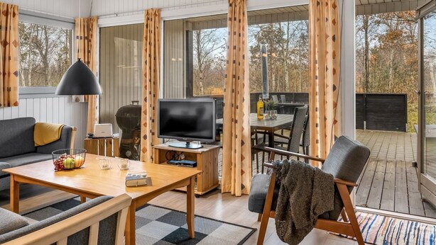 Una sala de estar moderna con televisor, sofá y comedor.