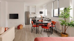 Un appartement moderne doté d’un coin repas, d’une kitchenette et d’un téléviseur fixé au mur.
