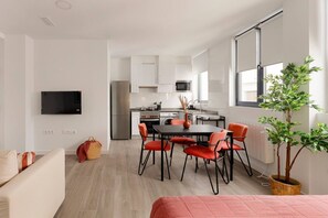 Ein modernes Apartment mit Essbereich, Küchenzeile und einem an der Wand befestigten Fernseher.