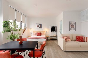 Ein modernes Hotelzimmer mit Bett, Sofa, Esstisch und Stühlen.