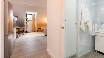 Eine moderne Küche mit Kühlschrank, ein Essbereich mit Stühlen und Tisch sowie ein Badezimmer mit Dusche und Handtuchhalter.
