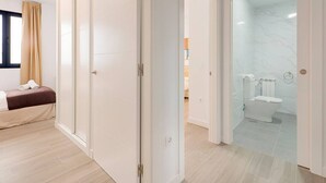 A hotel room with a bed, a wardrobe, a bathroom with a toilet and shower, and a glass door leading to another room. - 644D2 Apartamento 5p Sobrecantu (Oviedo)