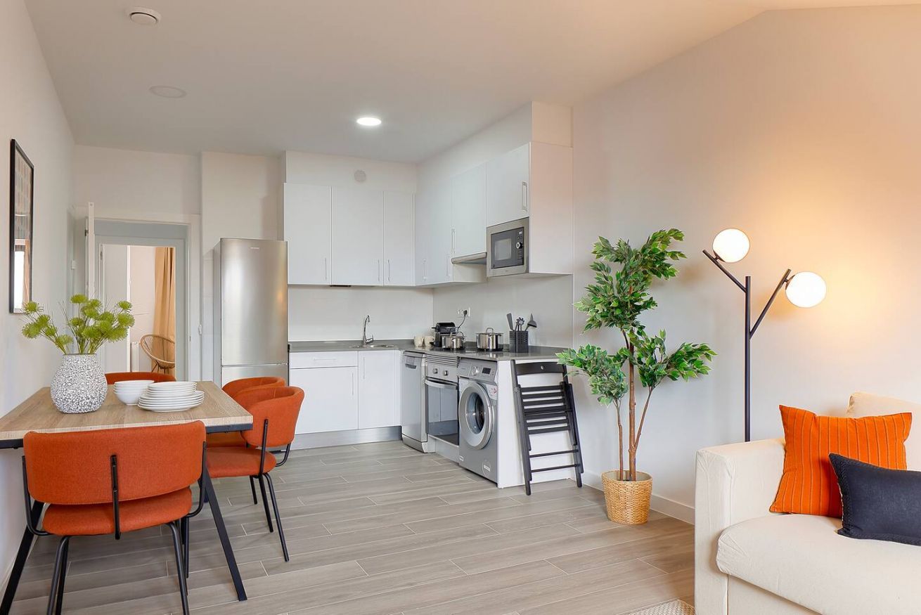 A modern kitchen with white cabinets, a built-in oven, and a microwave.