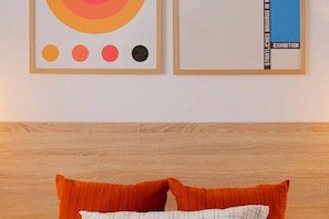 Una obra de arte enmarco con círculos abstractos y un cojín de estampado a rayas sobre una cama.