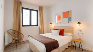 A bedroom with a bed, a chair, a table, a window with curtains, and wall art. - 644D2 Apartamento 5p Sobrecantu (Oviedo)