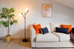 Ein Wohnzimmer mit einer Couch, einer Stehlampe und einem Blumentopf.