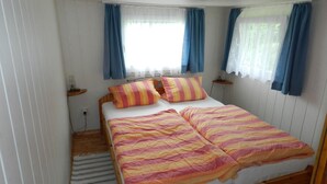 Un dormitorio con cama de madera, ropa de cama a rayas y cortinas azules.