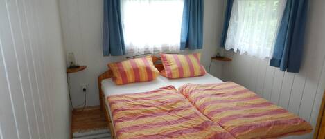 A bedroom with a wooden bed, striped bedding, and blue curtains.