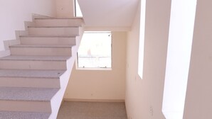 A staircase leading to a room with a window. - Hotel Rewa Regency (Huzur)