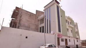 A multi-story building with a sign indicating a hotel. - Hotel Rewa Regency (Huzur)