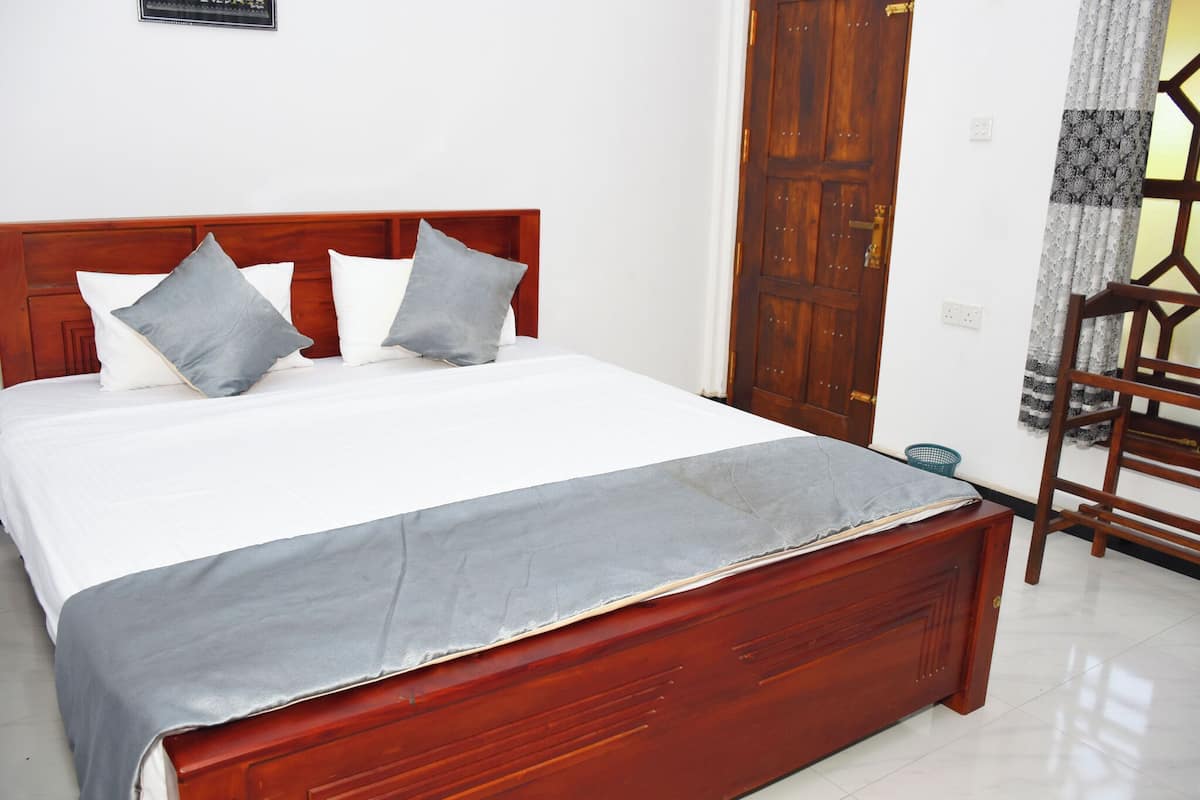 A bed with a wooden headboard, grey bedding, and a grey throw blanket.