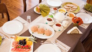 A table set for a meal with plates, cutlery, and a variety of dishes including noodles, fruit, and condiments. - Sasanda Villa (Tissamaharama)