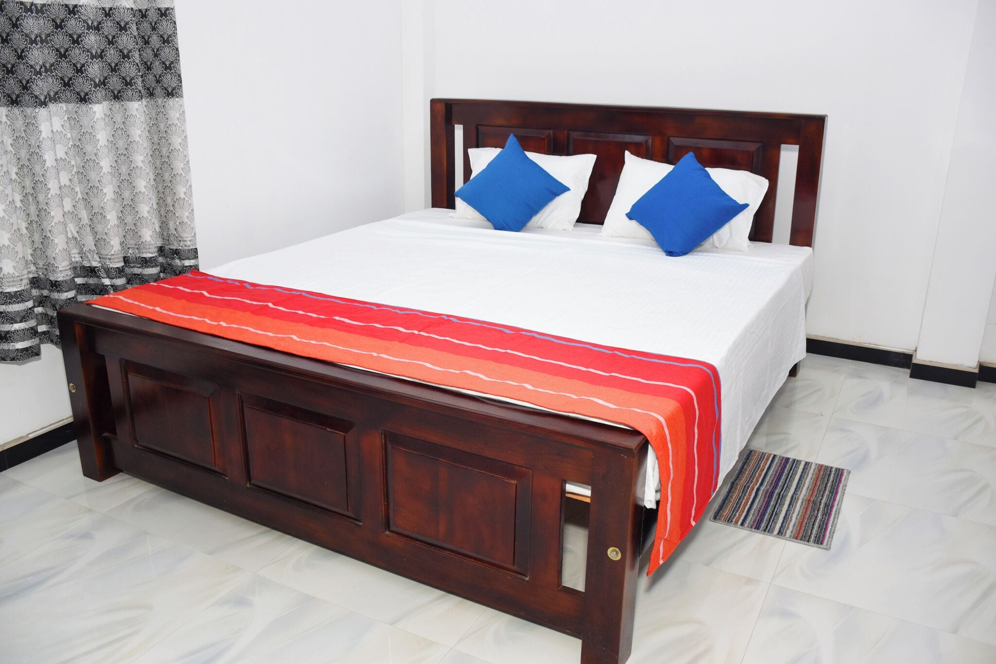 A neatly made bed with a wooden headboard, white bedding, and blue pillows.
