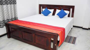 A neatly made bed with a wooden headboard, white bedding, and blue pillows.