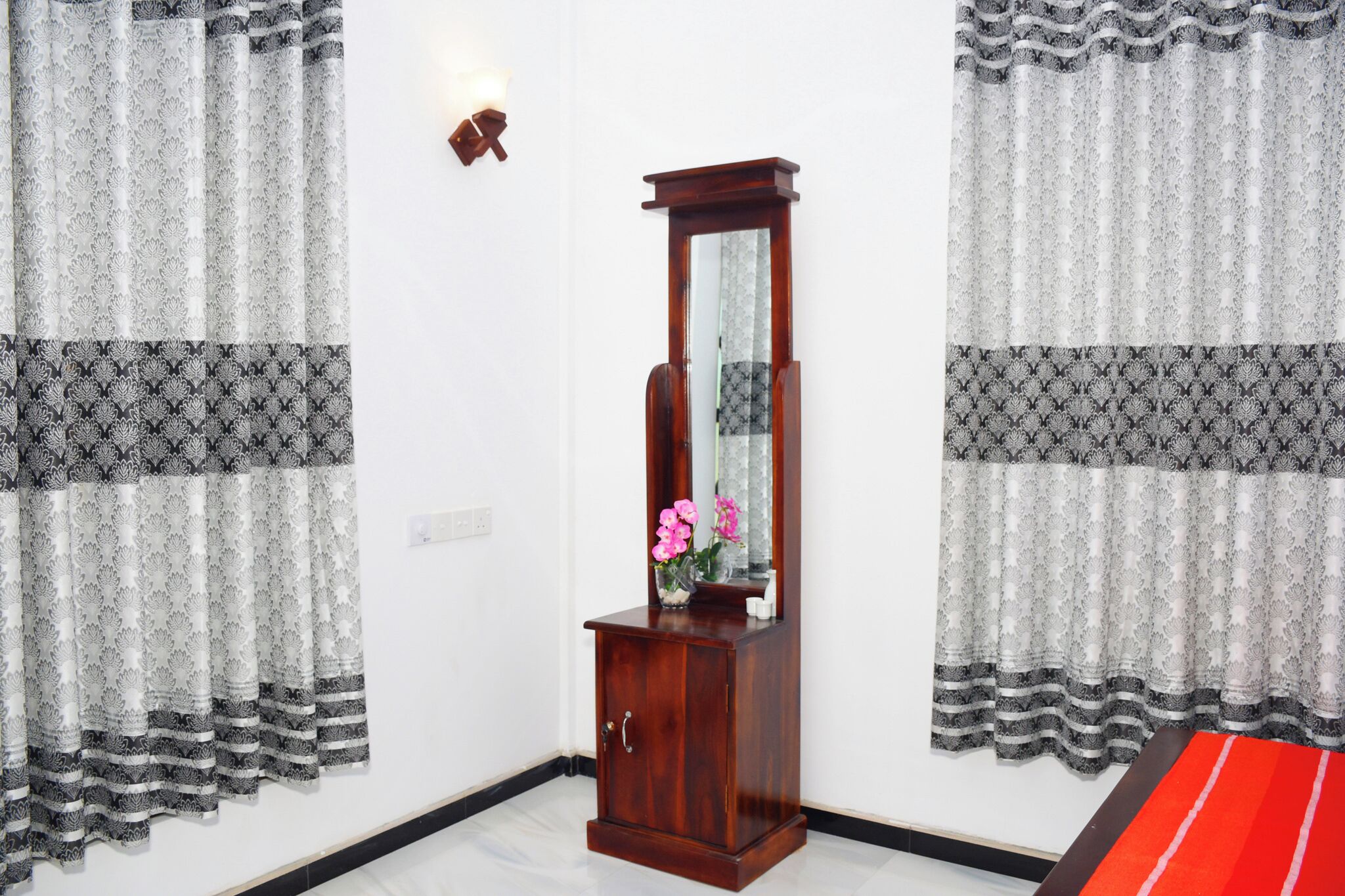 Een kamer met een houten kast, een spiegel en een vaas met bloemen.