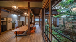 Un interior moderno con una mesa de comedor de madera, sillas y una zona de cocina con refrigerador y microondas.