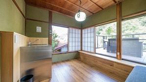 Una habitación pequeña de estilo tradicional, con techo de madera, lavamanos empotrado, puertas correderas tipo shoji y vistas a un jardín a través de ventanas amplias.