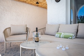 A cozy outdoor seating area with a sofa, two chairs, a small table, and a bottle of champagne. - Villa Los Pomelos - Capistrano! (Nerja)