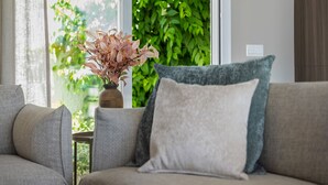 A living room with a sofa, a small table, and a vase with dried flowers.