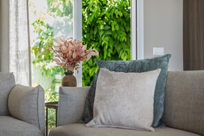 A living room with a sofa, a small table, and a vase with dried flowers. - Villa Los Pomelos - Capistrano! (Nerja)