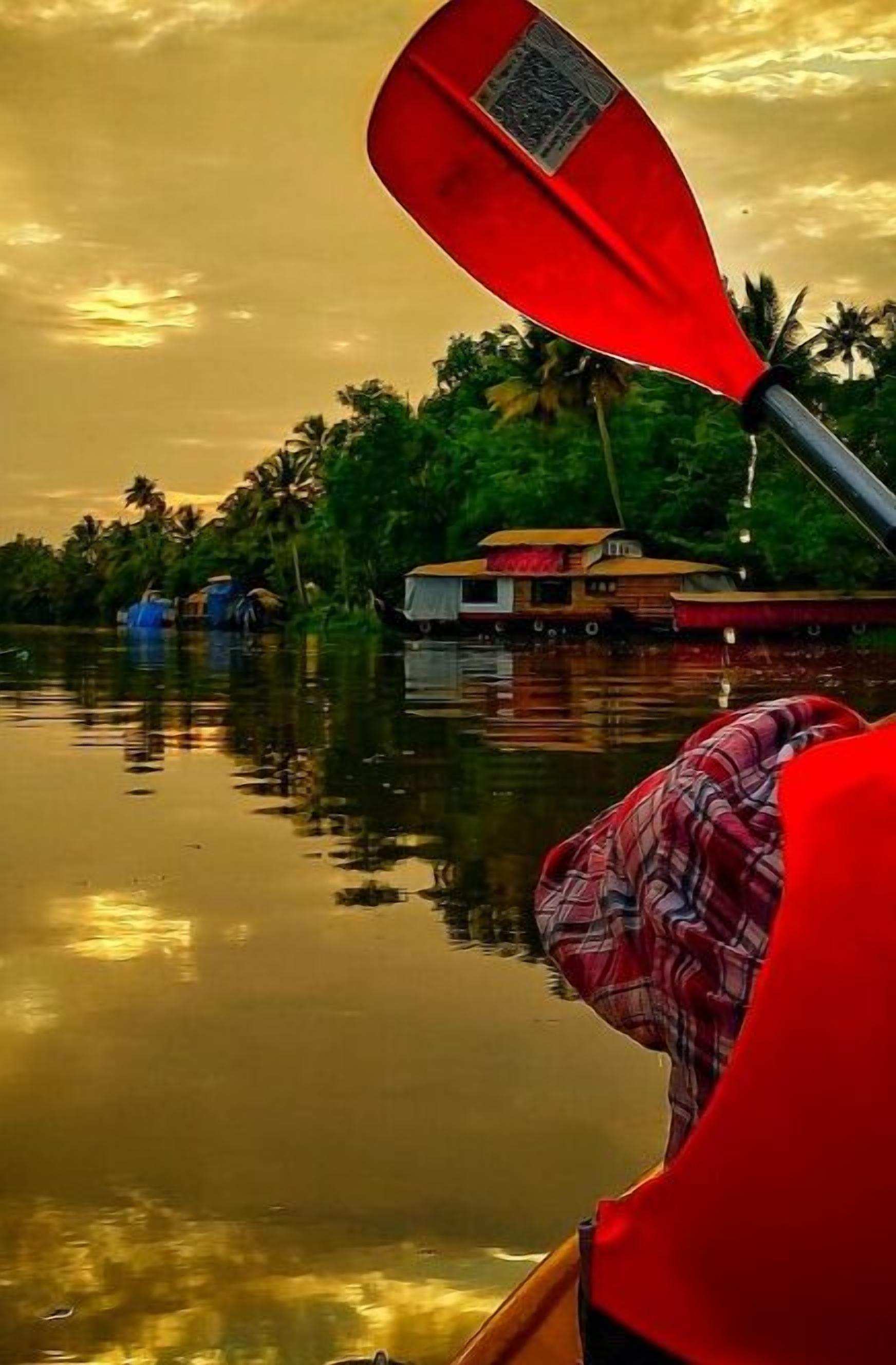 A calm river scene with a boat and a houseboat in the background.