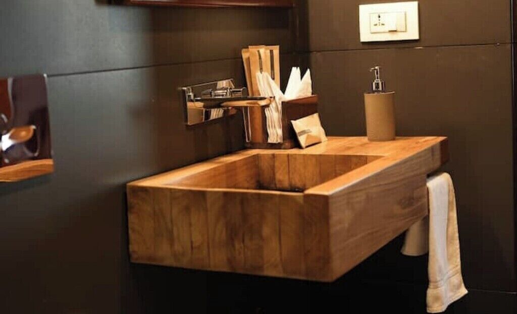 A wooden vanity with a sink, towel, and toiletries.