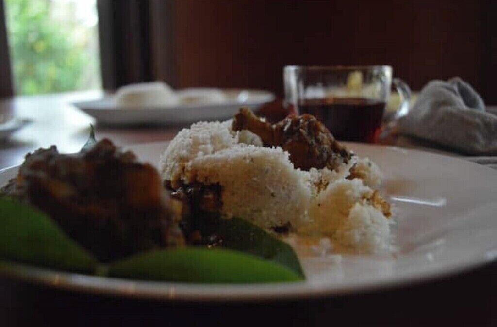 Une assiette de riz et de viande, un verre contenant un liquide sombre et une feuille verte.