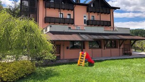 Une maison à deux étages avec un toboggan rouge dans le jardin.