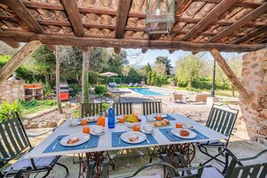 Un espace extérieur aménagé pour les repas, avec une piscine, une pergola en bois et du mobilier de jardin.