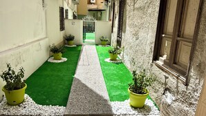 Une ruelle étroite avec un gazon synthétique vert et des plantes en pot.