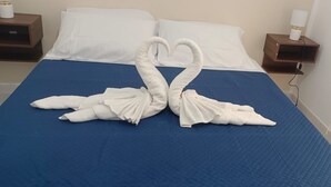 Un lit recouvert d’une couvre-lit bleue et orné de deux serviettes blanches disposées en forme de cygnes.
