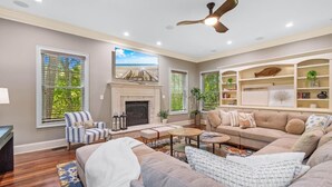 A living room with a fireplace, sofas, a coffee table, and a TV. - Seaclusion at the Beach (Pawleys Island)