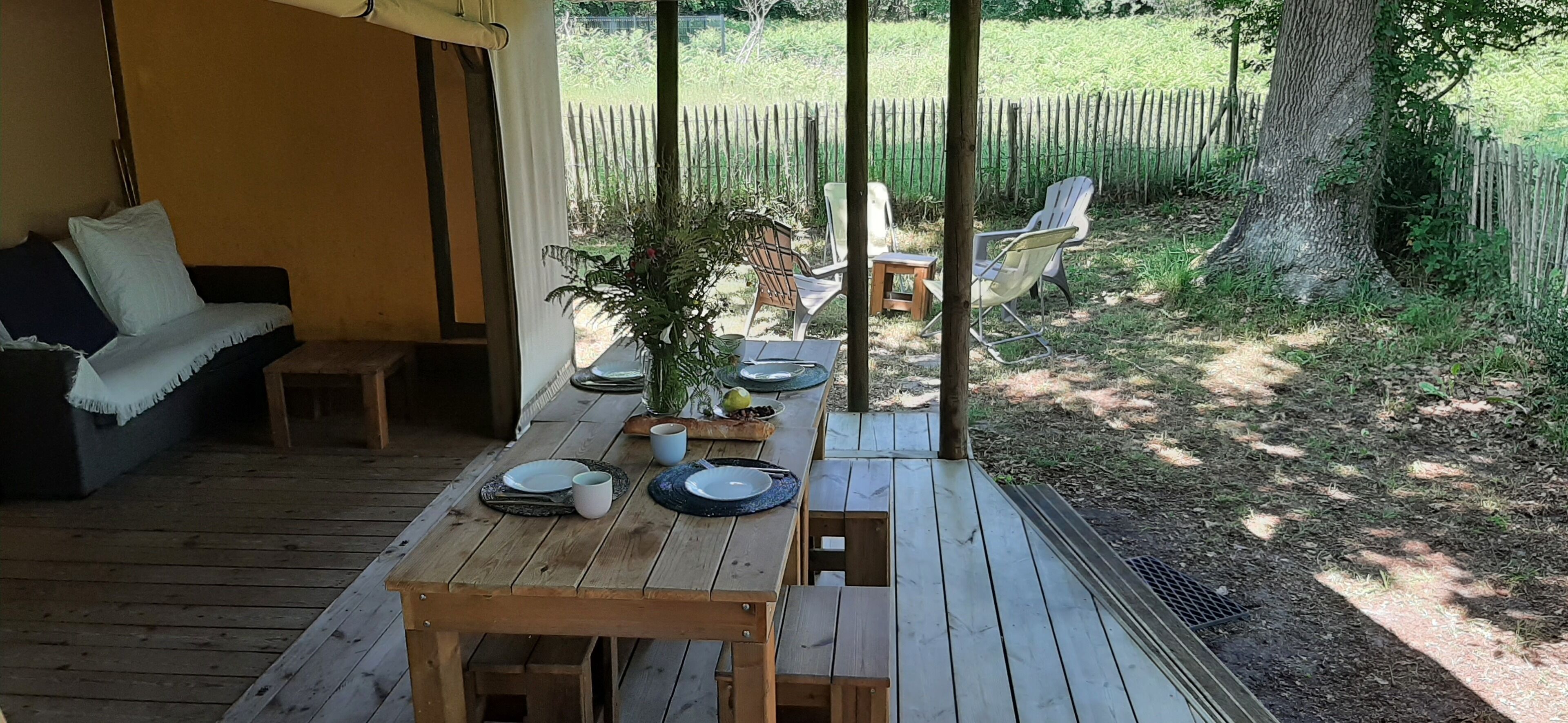 Eine Holzdiele mit Esstisch und Stühlen, sowie eine Couch mit Kissen.