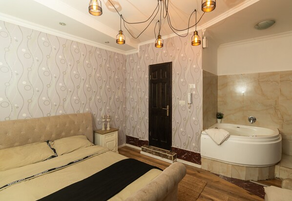 A bedroom with a bed, bedside table, and a bathroom with a bathtub. - Chateau Tel Aviv (Tel Aviv)