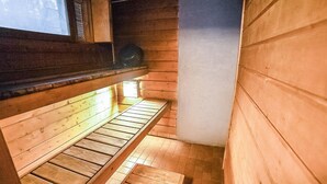 Una habitación de madera estrecha, con un banco a lo largo de una pared y una ventana encima.