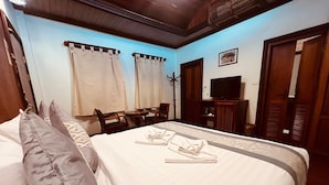 Una habitación de hotel con cama, almohadas, televisión y escritorio.