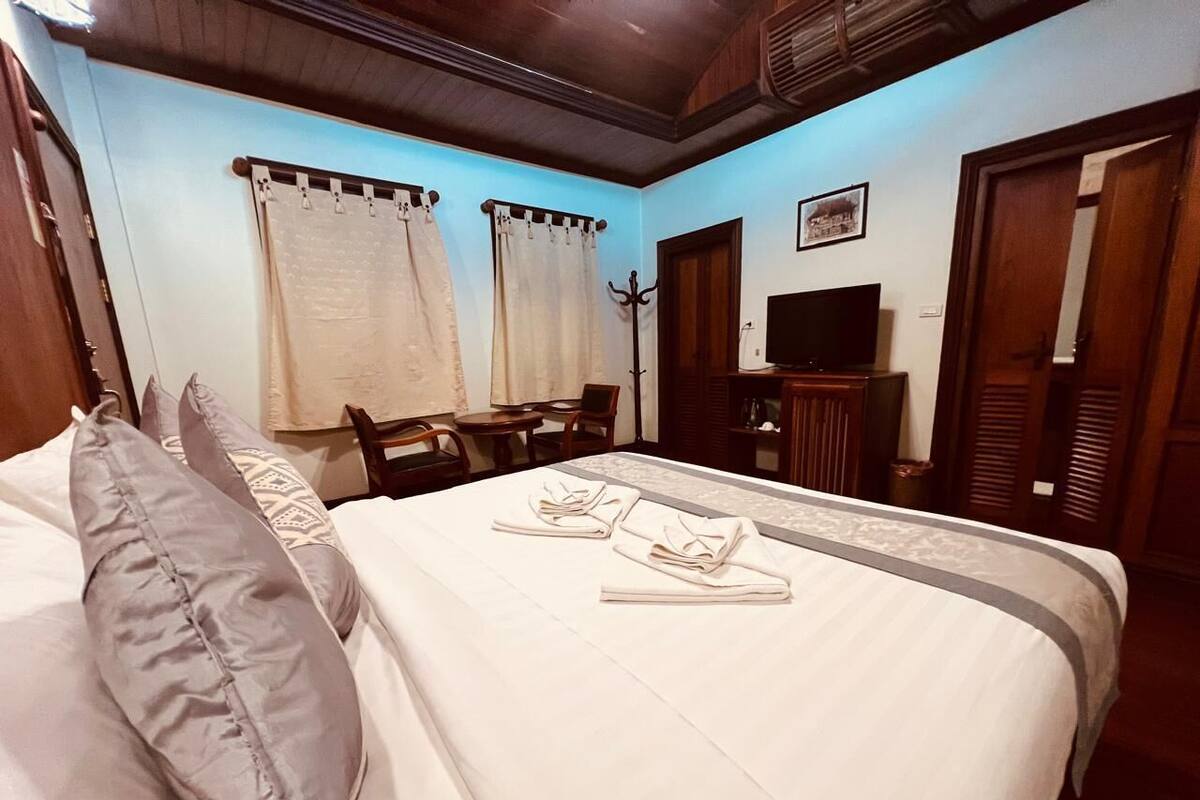 A hotel room with a bed, pillows, a TV, and a desk.