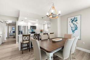 A modern kitchen with white cabinets, a stainless steel refrigerator, and a microwave. - Dela Park Place - Waterfront 2BDR/2BA with Den (Marco Island)